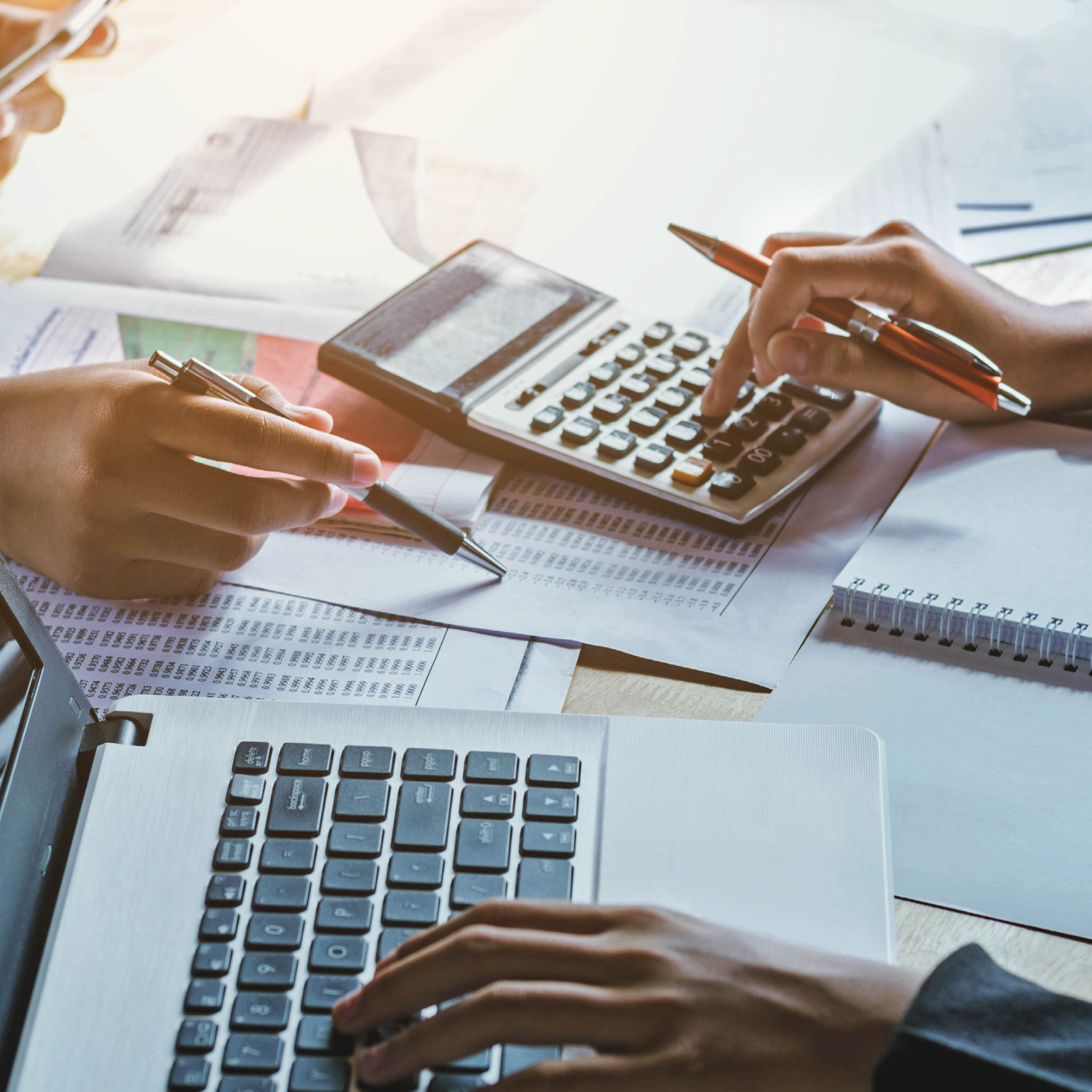 Photo of laptop and calculator with print outs of accounting documents